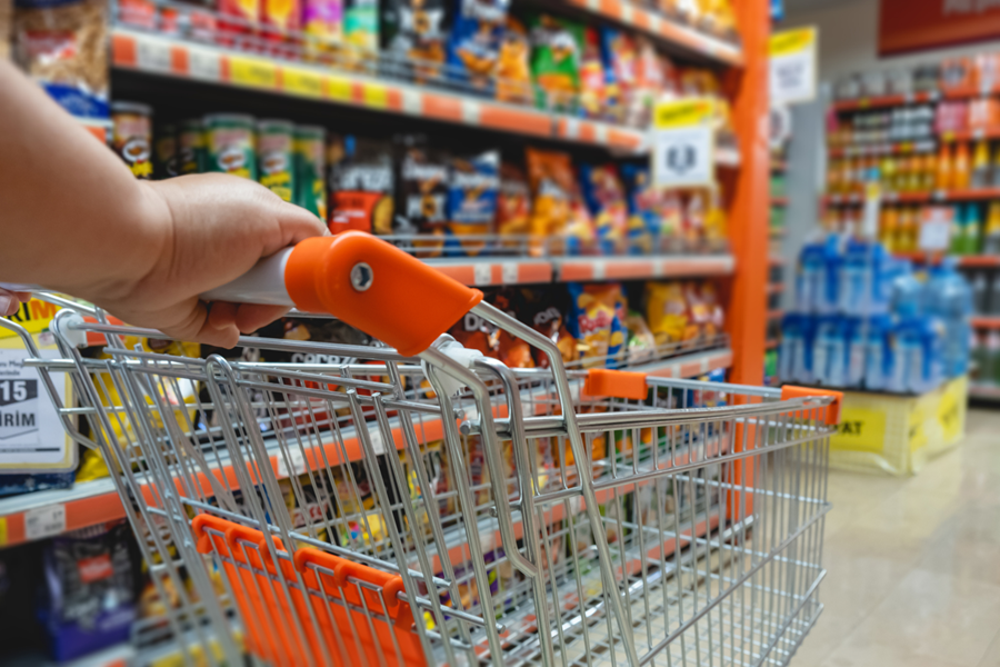 Pessoa empurrando um carrinho vazio dentro do supermercado.
